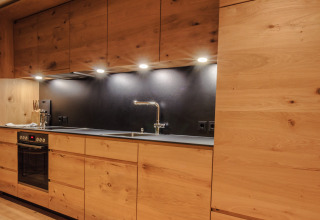 Moderne Küche im Premium Chalet des Wirthshof Resorts am Bodensee mit Holzfronten und stilvoller Beleuchtung.