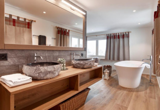 Bagno moderno al Glamping Atzmännig - PODhouses & Lodges See-Gaster con lavabi in pietra e vasca indipendente.