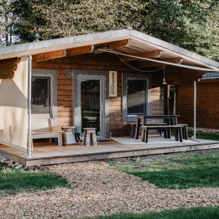 Knus houten chalet bij Destinature Dorf Südeifel met veranda, zitplek buiten en groene omgeving.
