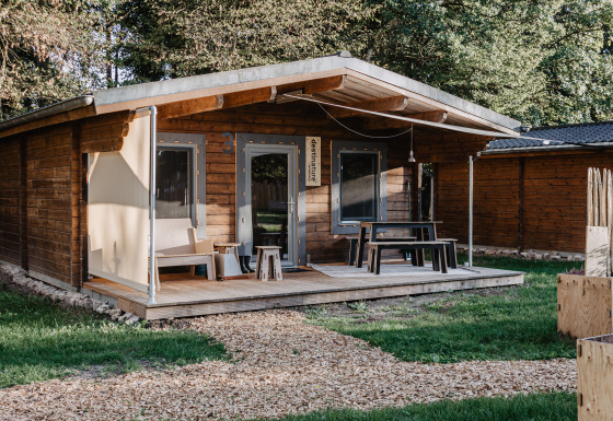 Knus houten chalet bij Destinature Dorf Südeifel met veranda, zitplek buiten en groene omgeving.