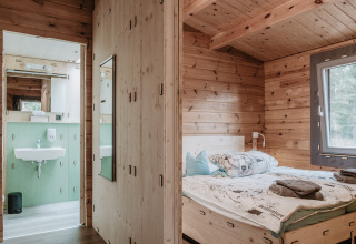 Interieur van een houten glamping-chalet met slaapkamer en badkamer bij Destinature Dorf Südeifel.