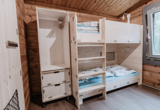 Gemütliches Glamping-Zimmer mit Holzstockbetten im Destinature Dorf Südeifel - Chalets Eifel, helle Einrichtung.