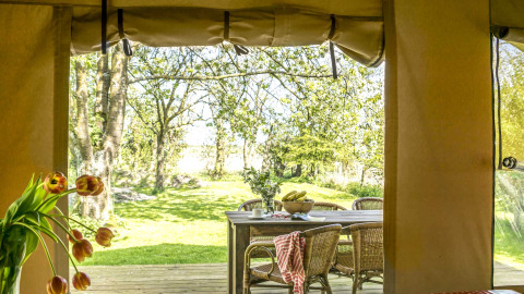 Uitzicht vanuit safaritent op buitentafel en groen bij Voedselbron Graauw safaritenten in Zeeland.