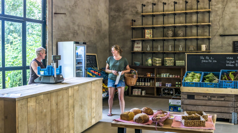 Una mujer compra en una acogedora tienda de granja en el glamping Voedselbron Graauw - Safaritenten Zeeland en Países Bajos.