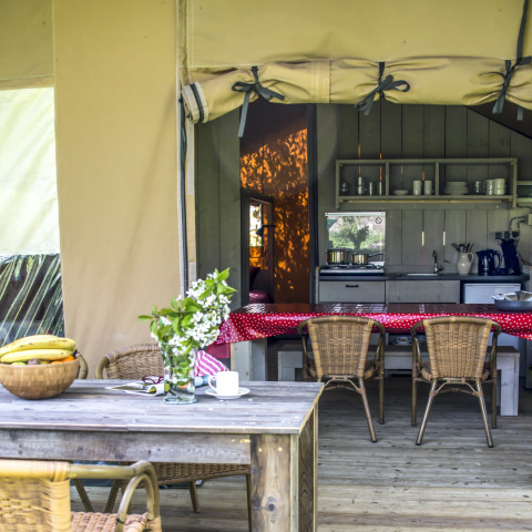 Cozy glamping kitchen and dining area with rustic furniture at Voedselbron Graauw Safaritenten Zeeland.