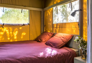 Alloggio glamping accogliente presso Safaritenten Zeeland con letto matrimoniale e tanta luce naturale dalle finestre.