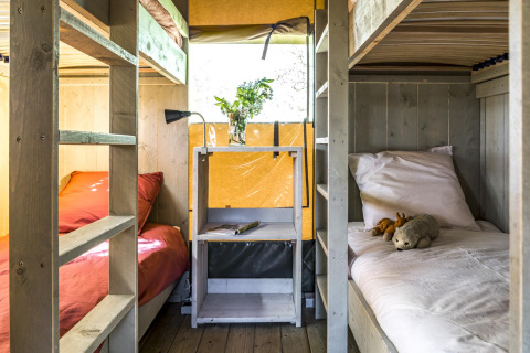 Interior of glamping tent at Voedselbron Graauw - Safaritenten Zeeland with bunk beds, window, and decor.