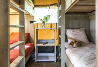 Interieur van glampingtent bij Voedselbron Graauw - Safaritenten Zeeland met stapelbedden en raam.