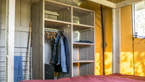 Interieur van een glamping tent bij Voedselbron Graauw - Safaritenten Zeeland, met kast en bed.