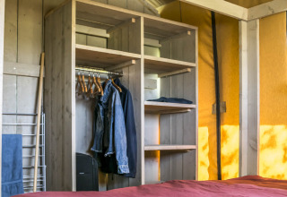 Interno di una tenda glamping presso Voedselbron Graauw - Safaritenten Zeeland con armadio e letto.
