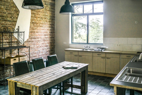 Communal kitchen at Voedselbron Graauw - Safaritenten Zeeland featuring wooden table, chairs, and window.