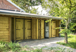 Servizi igienici esterni con porte in legno al glamping Voedselbron Graauw - Safaritenten Zeeland.