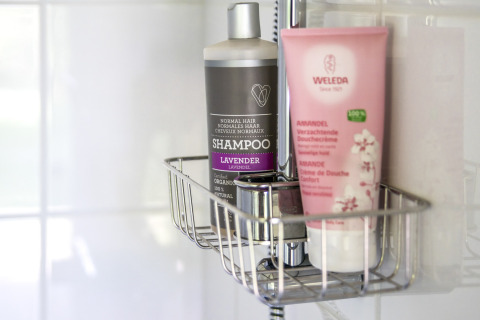 Shampoing et gel douche sur une étagère de salle de bain à Voedselbron Graauw - Safaritenten Zeeland glamping.