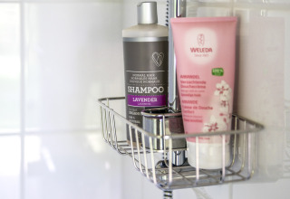 Shampoo und Duschgel in einem Badezimmerregal bei Voedselbron Graauw - Safaritenten Zeeland Glamping.