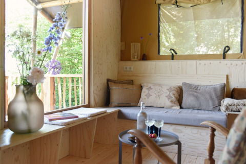 Cozy glamping accommodation with wooden floors, sofa, large windows at Smûk Recreatie - Lodgetenten Friesland.