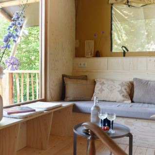 Gemütliche Glamping-Unterkunft mit Holzboden, Sofa und großen Fenstern bei Smûk Recreatie - Lodgetenten Friesland.