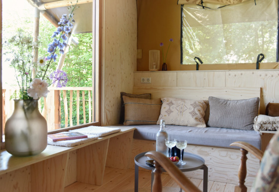 Cozy glamping accommodation with wooden floors, sofa, large windows at Smûk Recreatie - Lodgetenten Friesland.