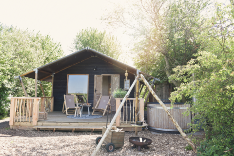 Glampingaccommodatie bij Smûk Recreatie - Lodgetenten Friesland met veranda, stoelen en buitenbad.