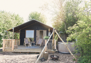 Udendørs glampinghytte ved Smûk Recreatie Lodgetenten Friesland, med veranda, træbad og natur omgivelser.