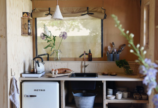 Accogliente cucina glamping a Smûk Recreatie Lodgetenten Friesland con frigo retrò e arredo rustico.