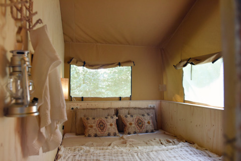 Interior de una tienda glamping en Smûk Recreatie - Lodgetenten Friesland con cama cómoda y ventanas.