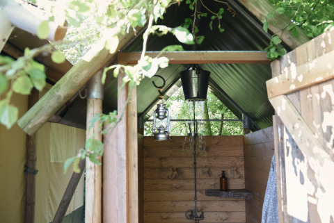 Doccia all'aperto in una tenda lodge glamping presso Smûk Recreatie in Frisia, immersa nella natura.