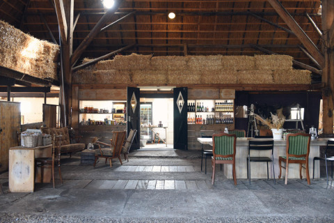 Rustic glamping interior at Smûk Recreatie - Lodgetenten Friesland featuring hay bales, lounge and dining areas.