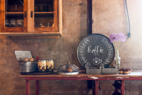 Acogedor rincón de café en alojamiento glamping rústico con café, tarros y flores frescas en la mesa.