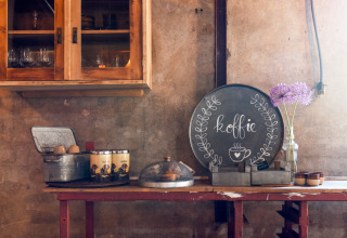 Angolo caffè accogliente in un alloggio glamping rustico con barattoli di caffè, zucchero e fiori freschi.