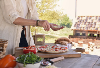 Person forbereder pizza udendørs ved Smûk Recreatie - Lodgetenten Friesland glamping i det fri.