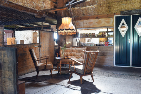 Interno rustico con poltrone vintage e lampada a Smûk Recreatie - Lodgetenten Friesland per il glamping.