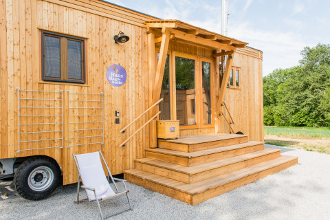 Holzverkleidetes Glamping-Unterkunft SONNENTOR - Lofts Oostenrijk mit Terrasse und Liegestuhl im Freien.