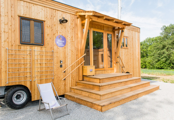 Holzverkleidetes Glamping-Unterkunft SONNENTOR - Lofts Oostenrijk mit Terrasse und Liegestuhl im Freien.