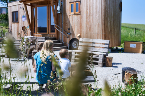 Famille assise devant un loft en bois Sonnentor en Autriche, entourée de verdure et de lumière naturelle.