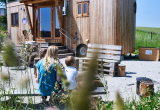 Famiglia seduta davanti a un loft in legno Sonnentor in Austria, circondata da verde e luce naturale.
