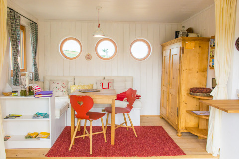 Gezellig interieur van SONNENTOR - Lofts Oostenrijk glamping met houten meubels en ronde ramen.
