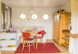 Acogedor interior en SONNENTOR - Lofts Oostenrijk glamping con muebles de madera y ventanas redondas.