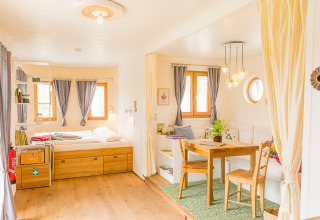 Lyst og hyggeligt glampingophold i SONNENTOR - Lofts Oostenrijk med seng, spisebord og afslapningsområde.