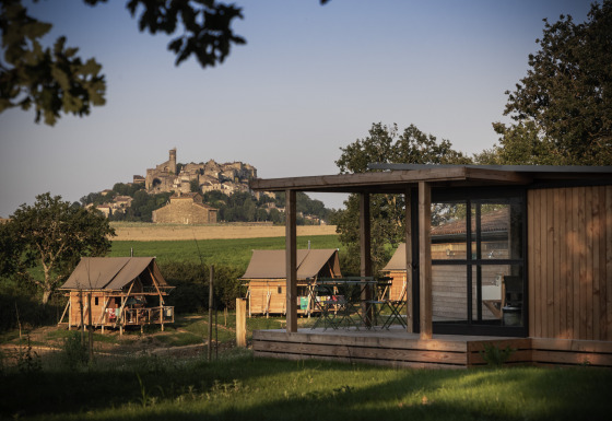 Glamping-Unterkünfte bei Camping Huttopia Pays de Cordes Sur Ciel mit Blick auf das Dorf in Occitanie.