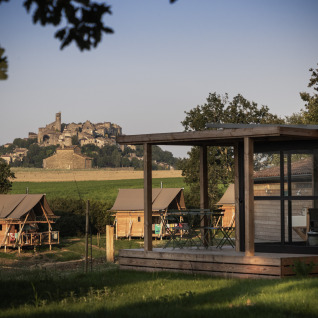 Glamping bij Camping Huttopia Pays de Cordes Sur Ciel met zicht op een dorp in het landschap van Occitanië.