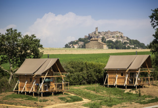To glamping-hytter på Camping Huttopia Pays de Cordes Sur Ciel i Occitanie, Frankrig, med udsigt til by på bakke.