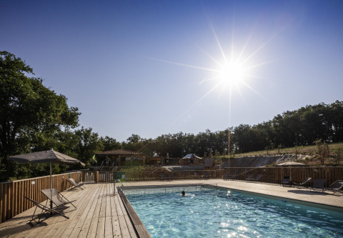 Piscine extérieure avec transats et parasols au Camping Huttopia Pays de Cordes Sur Ciel sous un soleil éclatant.