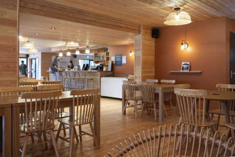 Gezellige caféruimte met houten meubilair bij Camping Huttopia Pays de Cordes Sur Ciel - Glamping Occitanië.