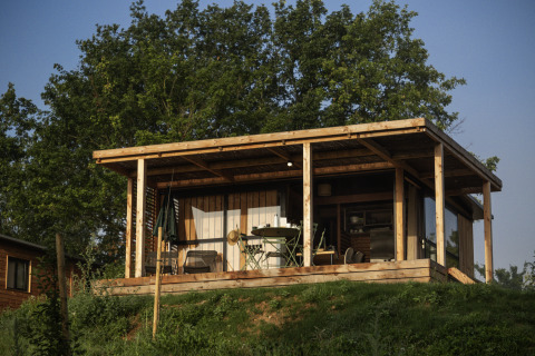 Glamping-Unterkunft bei Camping Huttopia Pays de Cordes Sur Ciel in Occitanie, Holzhaus mit Terrasse.