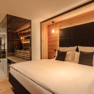 Luxe spa-chaletaccommodatie in Wirthshof Resort aan de Bodensee met moderne slaapkamer en glazen wand.