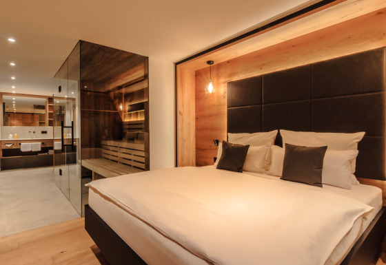 Luxe spa chalet bij Wirthshof Resort aan de Bodensee met modern ingerichte slaapkamer en glazen wand.