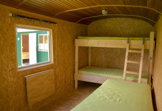 Indvendigt billede af et glampingværelse på Camping Böhmeschlucht - Pipowagen Nedersaksen med køjesenge.
