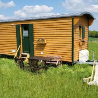 Glamping accommodatie bij Ferienhof Jeiler - Pipowagen Noordrijn Westfalen, houten pipowagen op een groen veld.