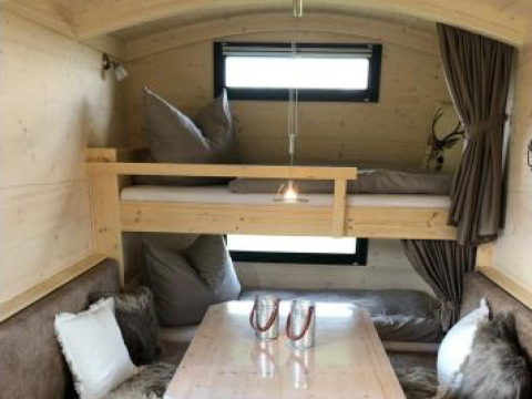 Interior de alojamiento glamping en Ferienhof Jeiler - Pipowagen Renania del Norte-Westfalia con cama y mesa.