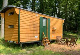 Alojamiento glamping en un Pipowagen amarillo en Ferienhof Jeiler, Noordrijn Westfalen, rodeado de bosque.